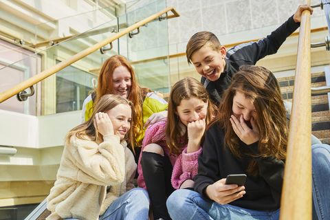group of teenage girls in a shopping mall, checking their mobile phones