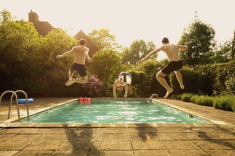 Rear view of men jumping in swimming pool during summer rear view of men jumping in swimming pool during summer