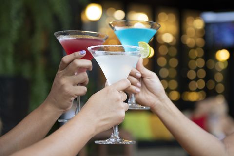Three arms holding three different colored drinks clink martini glasses three arms holding three different colored drinks clink martini glasses