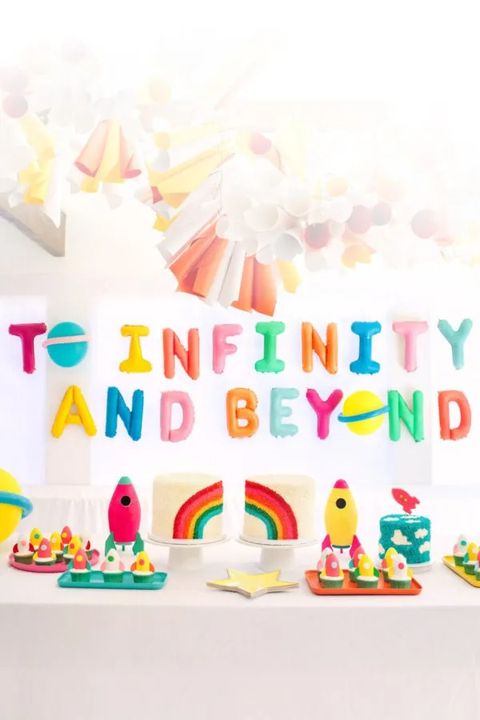 a first birthday party with a rocket theme includes a to infinity and beyond banner and rocket shaped food a first birthday party with a rocket theme includes a to infinity and beyond banner and rocket shaped food
