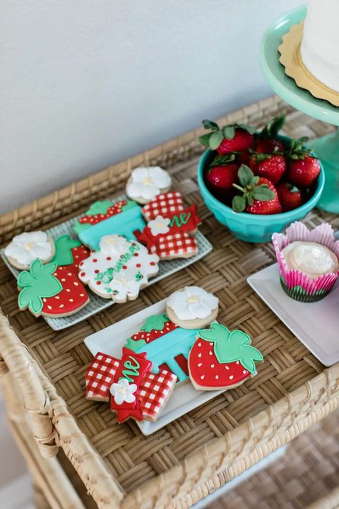 Berry shaped cookies and actual strawberries are displayed at a berry themed first birthday party berry shaped cookies and actual strawberries are displayed at a berry themed first birthday party