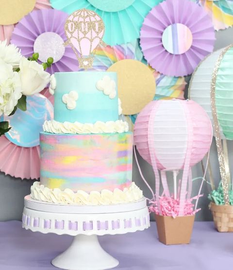 A first birthday party with a hot air balloon theme includes a cake with a balloon topper and paper lanterns made to look like hot air balloons a first birthday party with a hot air balloon theme includes a cake with a balloon topper and paper lanterns made to look like hot air balloons