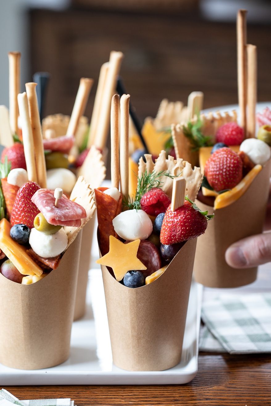 a tray of charcuterie cups with cheese, fruit and meat