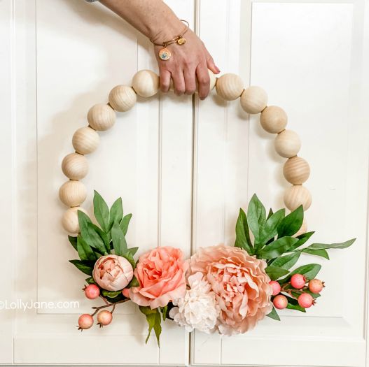 a wreath made out of large wooden beads and fake flowers