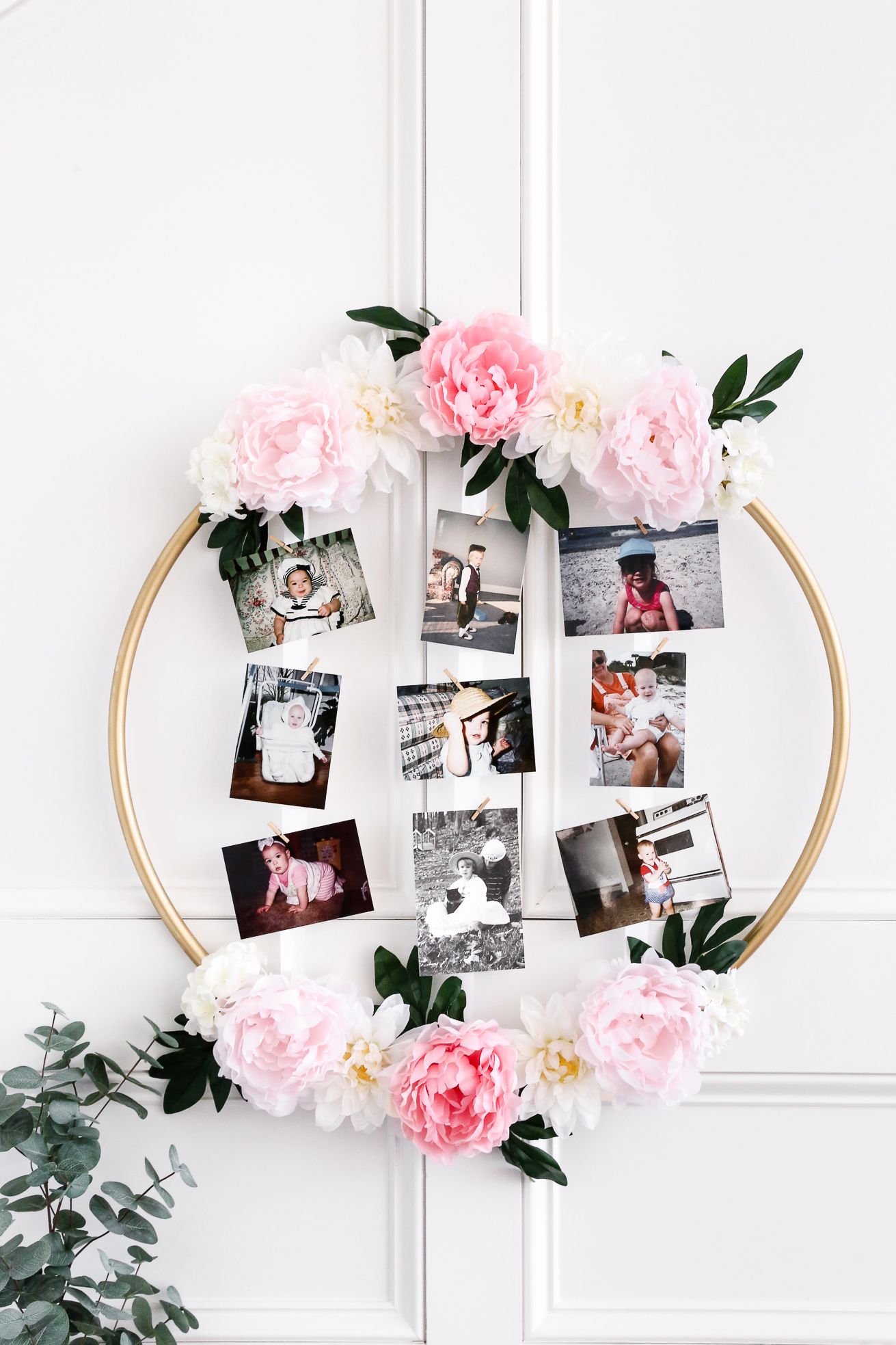 a hula hoop decorated with flowers holds a grid of baby photos, a great baby shower idea